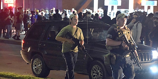 Kyle Rittenhouse, left, with backwards cap, walks along Sheridan Road in Kenosha, Wis., on Tuesday with another armed civilian. (Adam Rogan/The Journal Times via AP)