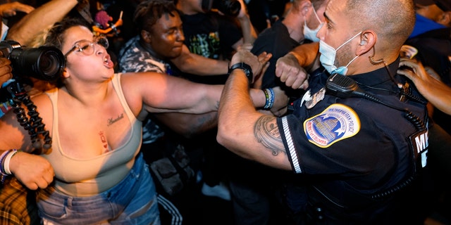 Metropolitan Police are confronted by protestors as police carry away a handcuffed protester along a section of 16th Street, Northwest, renamed Black Lives Matter Plaza, Thursday night, Aug. 27, 2020, in Washington, D.C., after President Donald Trump had finished delivering his acceptance speech from the White House South Lawn. (AP Photo/Julio Cortez)