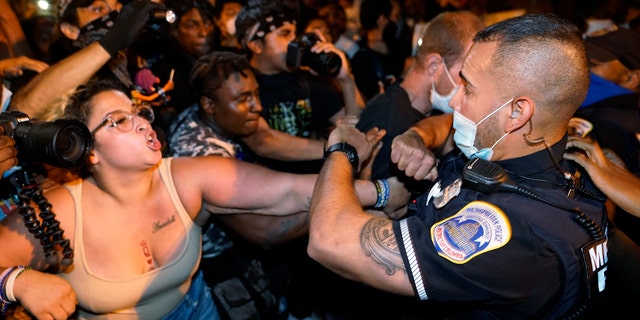 Metropolitan Police are confronted by protestors as police carry away a handcuffed protester along a section of 16th Street, Northwest, renamed Black Lives Matter Plaza, Thursday night, Aug. 27, 2020, in Washington, D.C., after President Donald Trump had finished delivering his acceptance speech from the White House South Lawn. (AP Photo/Julio Cortez)