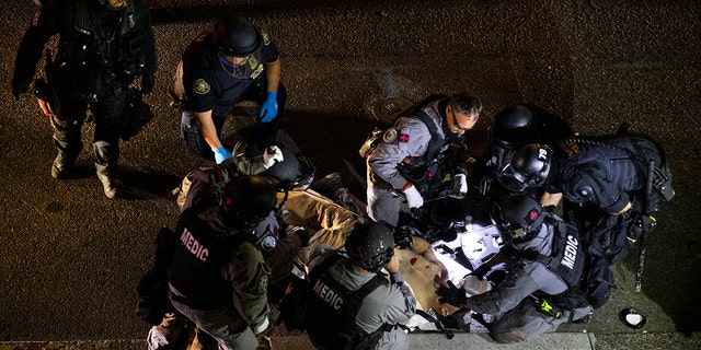 A man is treated after being shot Saturday, Aug. 29, 2020, in Portland, Ore. It wasn’t clear if the fatal shooting late Saturday was linked to fights that broke out as a caravan of about 600 vehicles was confronted by counterdemonstrators in the city’s downtown. (AP Photo/Paula Bronstein)