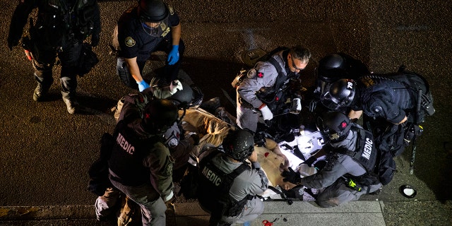 A man is treated after being shot Saturday, Aug. 29, 2020, in Portland, Ore. It wasn't clear if the fatal shooting late Saturday was linked to fights that broke out as a caravan of about 600 vehicles was confronted by counterdemonstrators in the city's downtown. (AP Photo/Paula Bronstein)