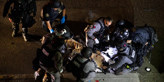 A man is treated after being shot Saturday, Aug. 29, 2020, in Portland, Ore. It wasn’t clear if the fatal shooting late Saturday was linked to fights that broke out as a caravan of about 600 vehicles was confronted by counterdemonstrators in the city’s downtown. (AP Photo/Paula Bronstein)