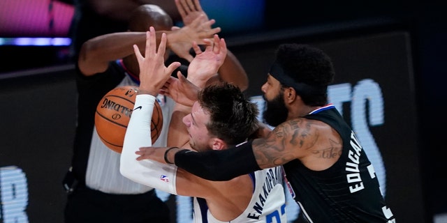 Dallas Mavericks' Luka Doncic (77) is fouled by Los Angeles Clippers' Marcus Morris Sr. during the first half of an NBA first round playoff game Sunday, Aug. 30, 2020, in Lake Buena Vista, Fla. (AP Photo/Ashley Landis)