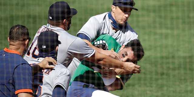 Oakland Athletics' Ramon Laureano is restrained by Houston Astro's Dustin Garneau after Laureano charged the dugout after being hit by a pitch thrown by Humberto Castellanos in the seventh inning of a baseball game Sunday, Aug. 9, 2020, in Oakland, Calif.