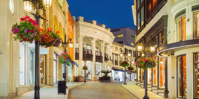 Photo of Rodeo Drive with illuminated stores in Beverly Hills, Calif., at twilight blue hour.