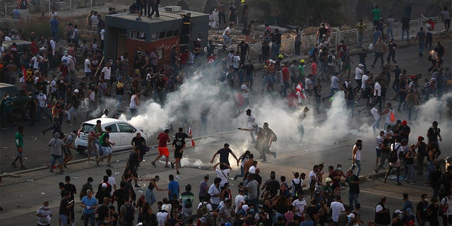 Demonstrators run away from tear gas fired by riot police during a protest following Tuesday's blast, in Beirut, Lebanon, Aug. 8.