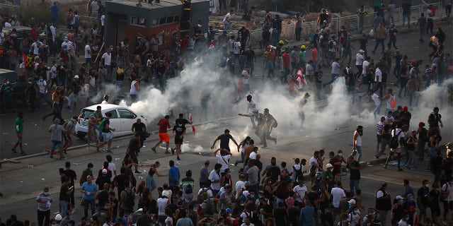 Demonstrators run away from tear gas fired by riot police during a protest following Tuesday's blast, in Beirut, Lebanon August 8, 2020. REUTERS/Hannah McKay - RC2S9I91Y6H3