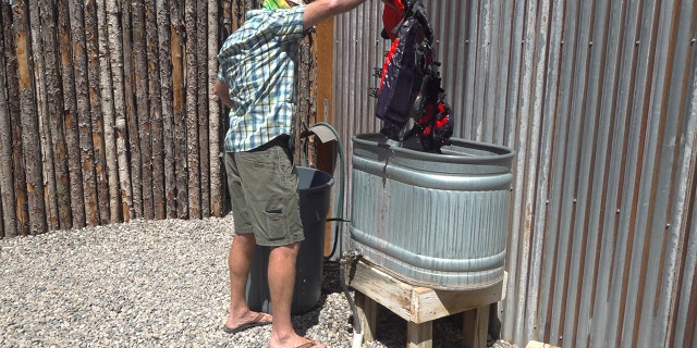 Matthew Gontram, owner of New Mexico River Adventures, demonstrates the business' new cleaning procedures, which include dunking life jackets into a cleaning solution and setting them aside for 48 hours.