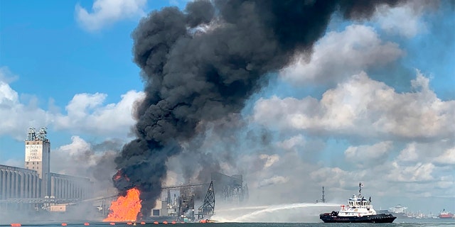 In this photo released by the U.S. Coast Guard, Coast Guard crews respond to a dredge on fire in the Port of Corpus Christi Ship Channel, Aug. 21, in Corpus Christi, Texas (U.S. Coast Guard via AP)