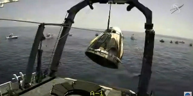 The capsule being lifted onto the SpaceX recovery ship Go Navigator. (NASA TV)