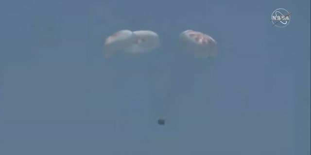 The capsule with its four main parachutes open.