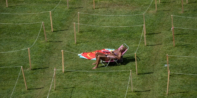 A sunbather checks her smartphone on a hot day of summer in Rivas Vaciamadrid, Spain, Wednesday, July 29, 2020.