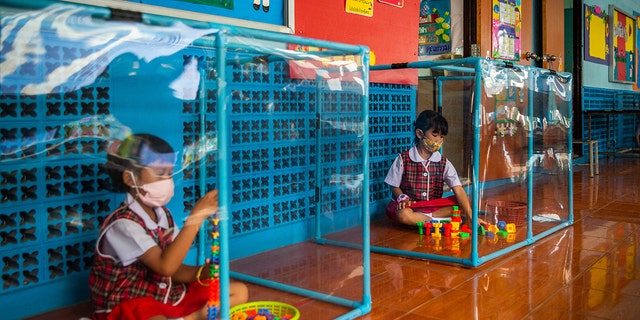 Thai kindergarten students wear face masks as they play in screened-in play areas used for social distancing at the Wat Khlong Toey School in Bangkok. (Getty Images)