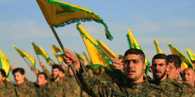 FILE - In this Feb. 13, 2016 file photo, Hezbollah fighters hold flags as they attend the memorial of their slain leader Sheik Abbas al-Mousawi, who was killed by an Israeli airstrike in 1992, in Tefahta village, south Lebanon. (AP Photo/Mohammed Zaatari, File)