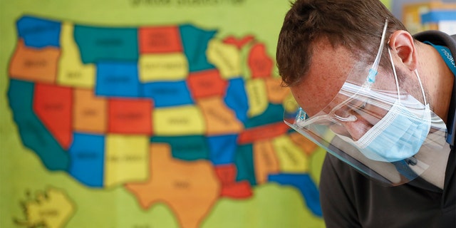 Custodian Joel Cruz cleans a desk in a classroom at Brubaker Elementary School in Des Moines, Iowa, in July. (AP Photo/Charlie Neibergall, File)