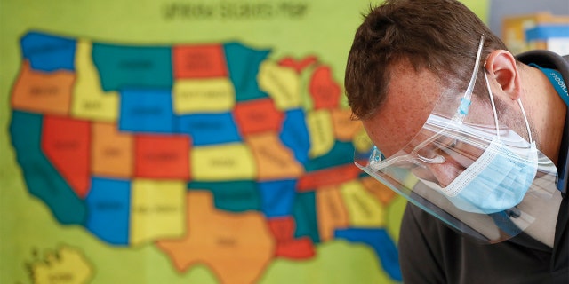 Custodian Joel Cruz cleans a desk in a classroom at Brubaker Elementary School in Des Moines, Iowa, in July. (AP Photo/Charlie Neibergall, File)