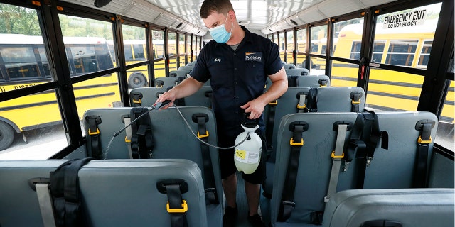 In this July 29, 2020, file photo, Des Moines Public Schools mechanic Kelly Silver cleans the interior of a school bus in Des Moines, Iowa.