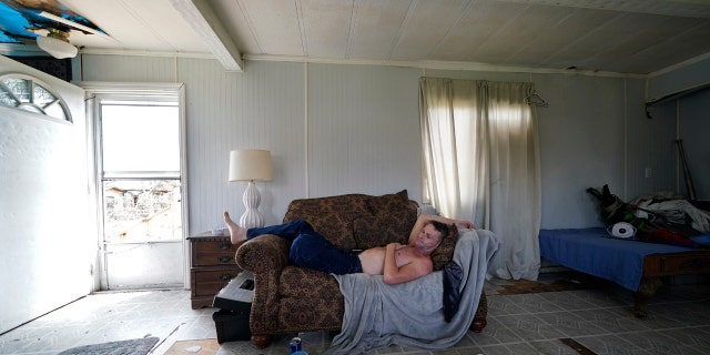 James Townley, who has a heart condition, lies on his couch with no electricity in his partially destroyed mobile home in Lake Charles, La., in the aftermath of Hurricane Laura, Sunday, Aug. 30, 2020.