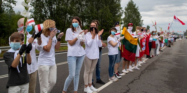 Supporters of Belarus opposition from Lithuania hold and wave historical Belarusian flags during the "Freedom Way", a human chain of about 50,000 strong from Vilnius to the Belarusian border, during a protest near Medininkai, Lithuanian-Belarusian border crossing east of Vilnius, Lithuania, Sunday, Aug. 23, 2020. In Aug. 23, 1989, around 2 million Lithuanians, Latvians, and Estonians joined forces in a living 600 km (375 mile) long human chain Baltic Way, thus demonstrating their desire to be free. Now, Lithuania is expressing solidarity with the people of Belarus, who are fighting for freedom today. (AP Photo/Mindaugas Kulbis)