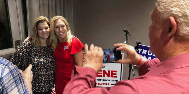 Supporters take photos with construction executive Marjorie Taylor Greene, background right, late Tuesday, Aug. 11, 2020, in Rome, Ga. Greene won the GOP nomination for northwest Georgia's 14th Congressional District. (AP Photo/Mike Stewart)