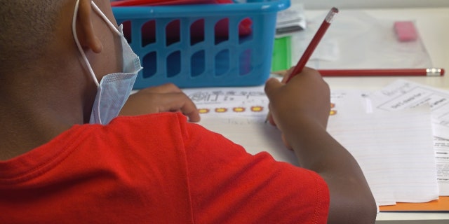 An elementary school student works on an assignment in class.