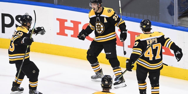 Boston Bruins center Patrice Bergeron (37) reacts with teammates Brad Marchand (63) Torey Krug (47) and Brandon Carlo (25) after scoring the game-winning goal against the Carolina Hurricanes during the second overtime period of an NHL Eastern Conference Stanley Cup playoff game in Toronto on Wednesday, Aug. 12, 2020. (AP)