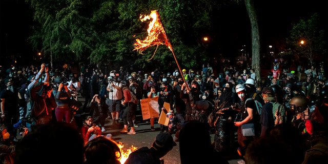 A demonstrator burns an American flag outside the Mark O. Hatfield United States Courthouse late Friday night during the protest on July 31, 2020 in Portland, Oregon. (ALISHA JUCEVIC/AFP via Getty Images)