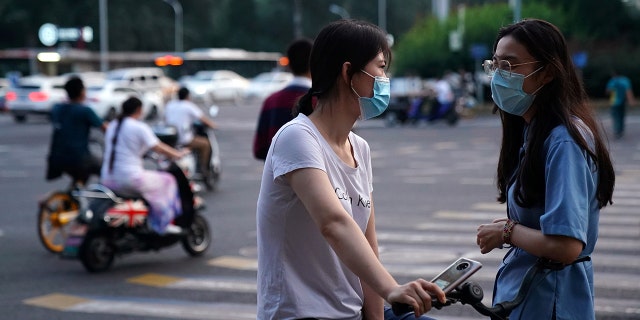 Women wearing face masks following the coronavirus disease (COVID-19) outbreak chat on a street in Beijing, China August 11, 2020. (REUTERS/Tingshu Wang)
