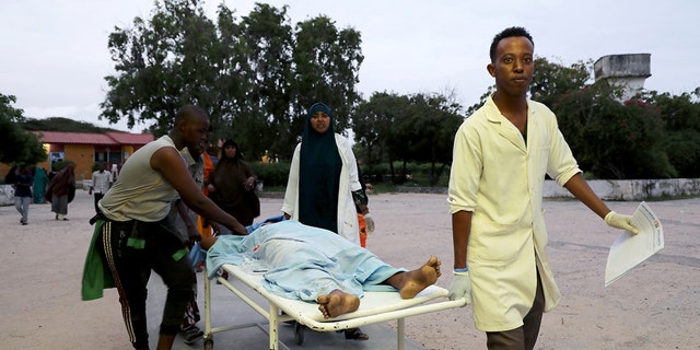 Paramedics and civilians carry an injured person on a stretcher at Madina hospital after a blast at the Elite Hotel in Lido beach in Mogadishu, Somalia August 16, 2020. (Reuters/Feisal Omar)