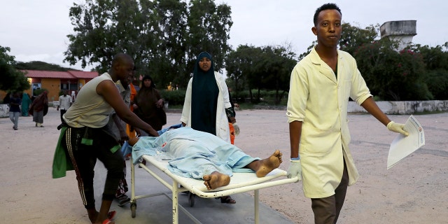 Paramedics and civilians carry an injured person on a stretcher at Madina hospital after a blast at the Elite Hotel in Lido beach in Mogadishu, Somalia August 16, 2020. (Reuters/Feisal Omar)