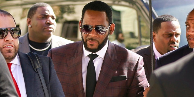 R&amp;B singer R. Kelly, center, arrives at the Leighton Criminal Court building for an arraignment on sex-related felonies in Chicago. Federal prosecutors announced charges Wednesday, Aug. 12, 2020, against three men accused of threatening and intimidating women who have accused Kelly of abuse, including one man suspected of setting fire to a vehicle in Florida.