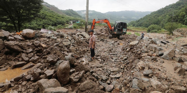 A man stands on road covered with mud and rocks after heavy rains in Chungju, South Korea, Sunday, Aug. 2, 2020.