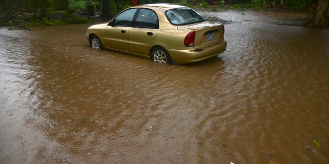 A car sits in flood waters caused by Tropical Storm Laura in Salinas, Puerto Rico, Saturday, Aug. 22, 2020. Laura began flinging rain across Puerto Rico and the Virgin Islands on Saturday morning and was expected to drench the Dominican Republic, Haiti and parts of Cuba during the day on its westward course.