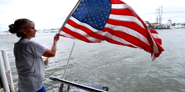 Liz Mcalpine pulls a flag from down her boat in Lake Pontchartrain as she prepares for Tropical storm Marco and Tropical storm Laura on August 23, 2020, in New Orleans, Louisiana. Both storms are expected to make landfall along the Louisiana coast within days of each other.