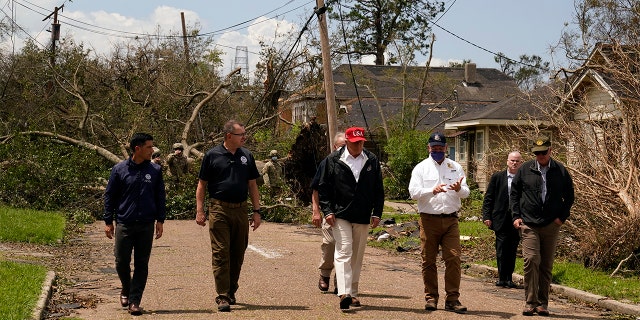 President Donald Trump talks with Louisiana Gov. John Bel Edwards, in white short, as he tours damage from Hurricane Laura, Aug. 29, in Lake Charles, La. (AP Photo/Alex Brandon)