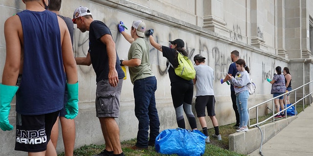 Volunteers clean graffiti from a high school near the Kenosha County Courthouse following another night of unrest on Aug. 25 in Kenosha, Wis. (Photo by Scott Olson/Getty Images)