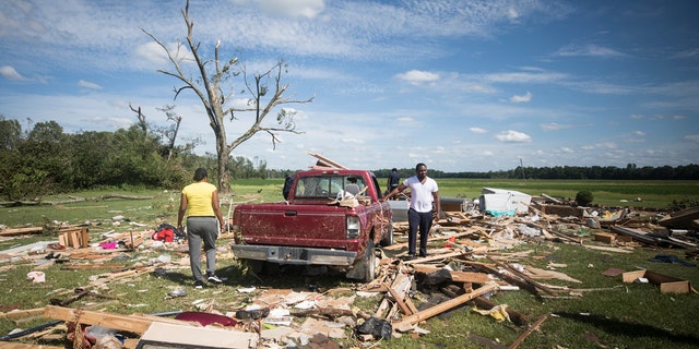 Relatives of a woman who was injured when a suspected tornado ripped through the area southeast of Windsor, N.C. sort through the rubble on Tuesday, Aug. 4, 2020.