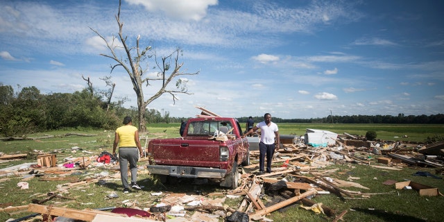 Relatives of a woman who was injured when a suspected tornado ripped through the area southeast of Windsor, N.C. sort through the rubble on Tuesday, Aug. 4, 2020.