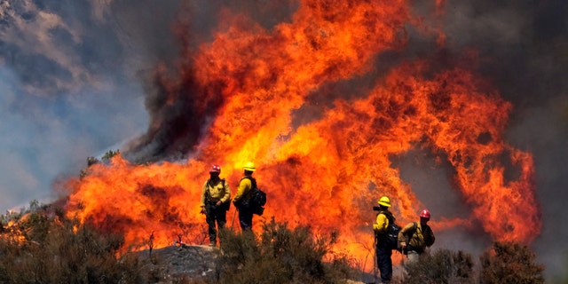 Firefighters watch the Apple Fire in Banning, Calif., Sunday, Aug. 2, 2020.