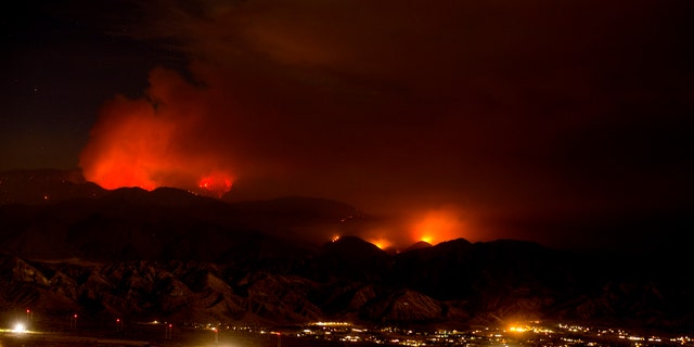 The Apple Fire burns behind mountains near Beaumont, Calif., Sunday, Aug. 2, 2020.