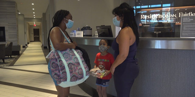 Gladys Vega, executive director of the Chelsea Collaborative, hands over a hotel key to Elizabeth Souffrant so she and her son don't have to sleep in her car.