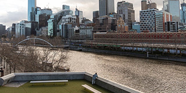 A lone man looks out toward the Yarra River and the empty Central Business District during lockdown in Melbourne, the captial city of Victoria state in Australia, on Aug. 5. Victoria state is considered a COVID-19 hotspot and has taken strict measures to prevent the spread of the virus. (AP Photo/Asanka Brendon Ratnayake)