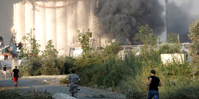 Lebanese security officers run to the scene of an explosion at the Beirut seaport on Tuesday, Aug 4. (AP Photo/Hussein Malla)