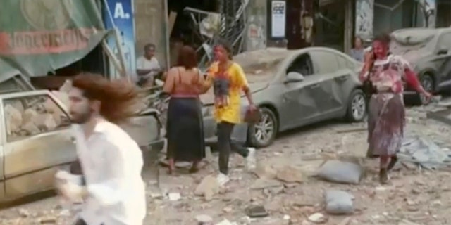 In this frame from video people walk down the street after an explosion in Beirut, Tuesday, Aug. 4, 2020. Explosions rocked Beirut, inflicting many injuries and damaging buildings in a large radius around the city’s port. (AP Photo)