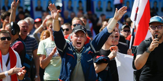 Workers with old Belarus national flags shout anti-Lukashenko slogans during a rally at the Minsk Motor Plant in Minsk, Belarus, on Monday to demand the resignation of Lukashenko. (AP Photo/Sergei Grits)