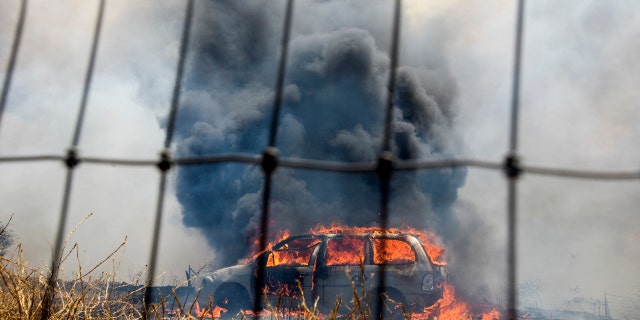 A brush fire burns a car at the Apple Fire in Cherry Valley, Calif., Saturday, Aug. 1, 2020.