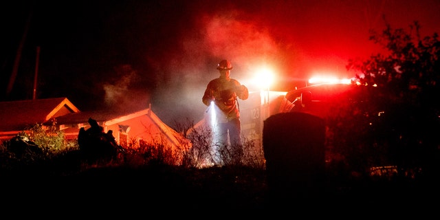 Firefighter Capt. Kelvin Patterson extinguishes hot spots while protecting a home as the Lake Fire burns in the Angeles National Forest, Calif., north of Santa Clarita on Thursday, Aug. 13, 2020.