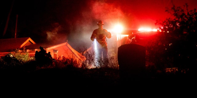 Firefighter Capt. Kelvin Patterson extinguishes hot spots while protecting a home as the Lake Fire burns in the Angeles National Forest, Calif., north of Santa Clarita on Thursday, Aug. 13, 2020.