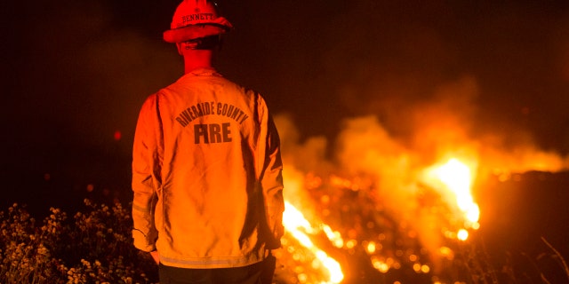 A firefighter watches a brush fire at the Apple Fire in Banning, Calif., Saturday, Aug. 1, 2020.