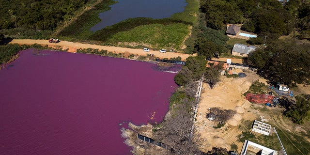 A road divides the Cerro Lagoon, where the water below the road is colored and the Waltrading S.A. tannery stands on the bank, bottom right, in Limpio, Paraguay, on Wednesday. (AP Photo/Jorge Saenz)